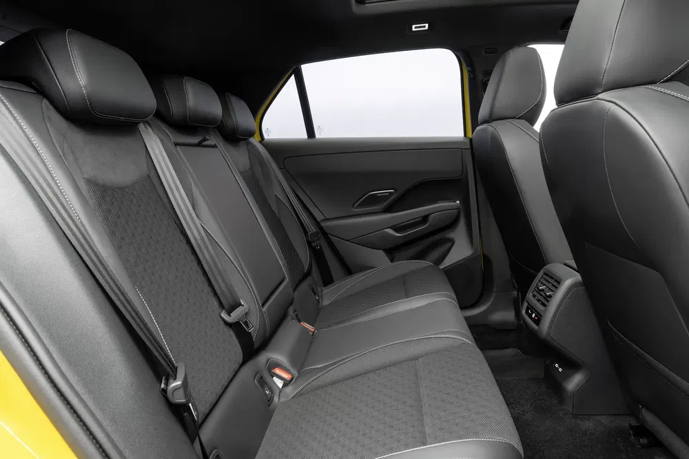 Intérieur arrière d'une voiture avec sièges en tissu noir et espace pour les passagers.
