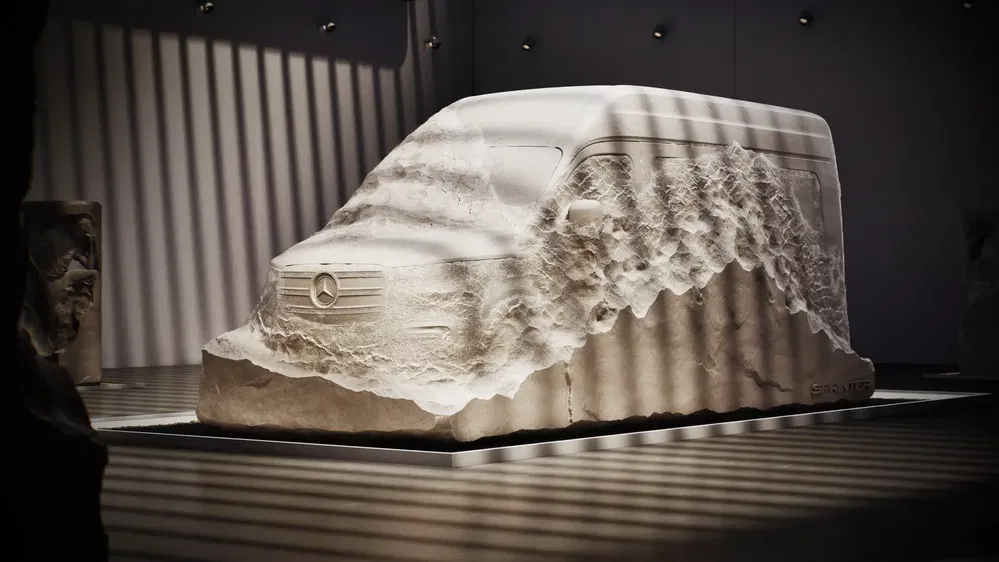 Sculpture artistique en pierre d'un Mercedes Sprinter dans une galerie moderne.