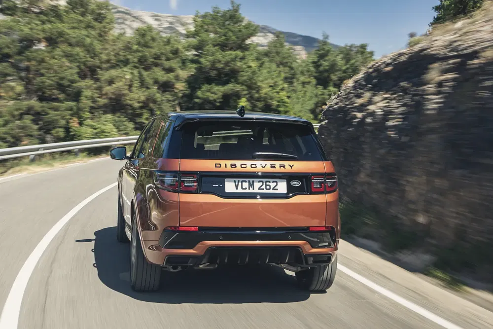 {"fr":"Land Rover Discovery marron sur route sinueuse bordée d'arbres et de montagnes.","nl":"Bruine Land Rover Discovery op een bochtige weg omgeven door bomen en bergen."}