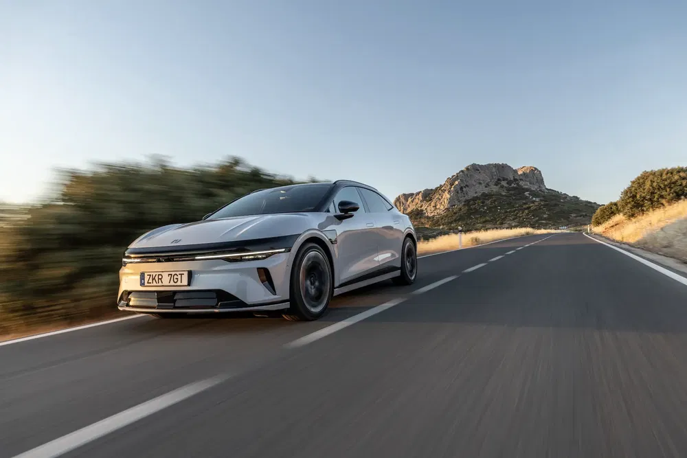 Kia EV6 grise roulant rapidement sur une route de campagne avec montagne en arrière-plan.
