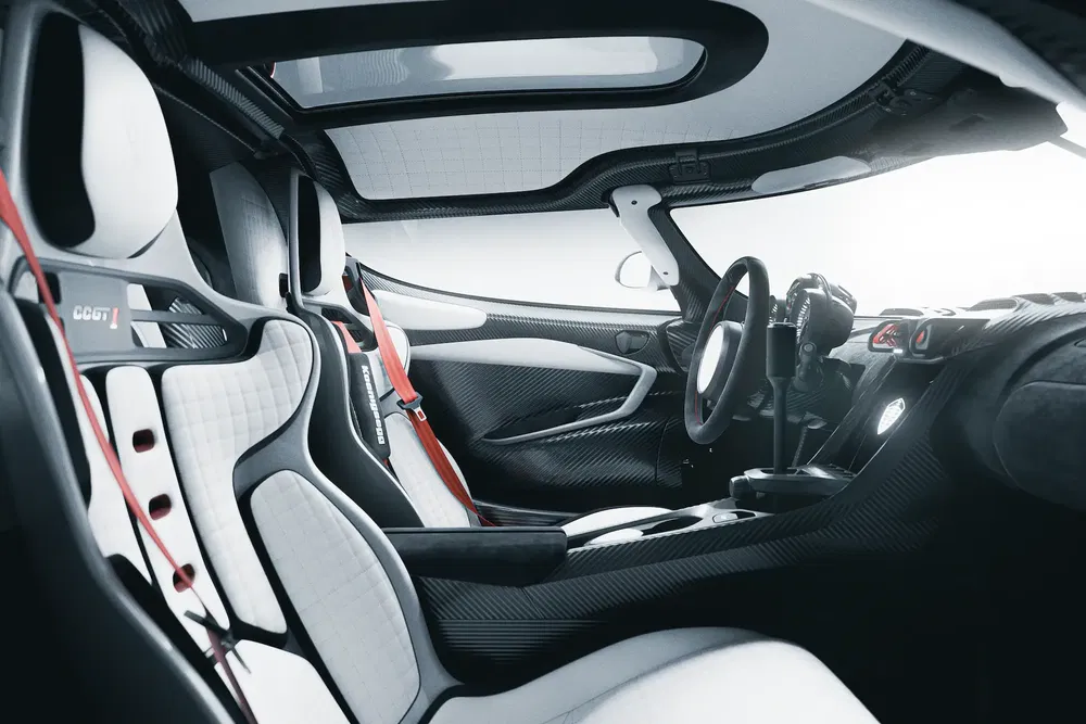 Intérieur de supercar CGT avec sièges en cuir blanc et ceintures rouges, design futuriste.