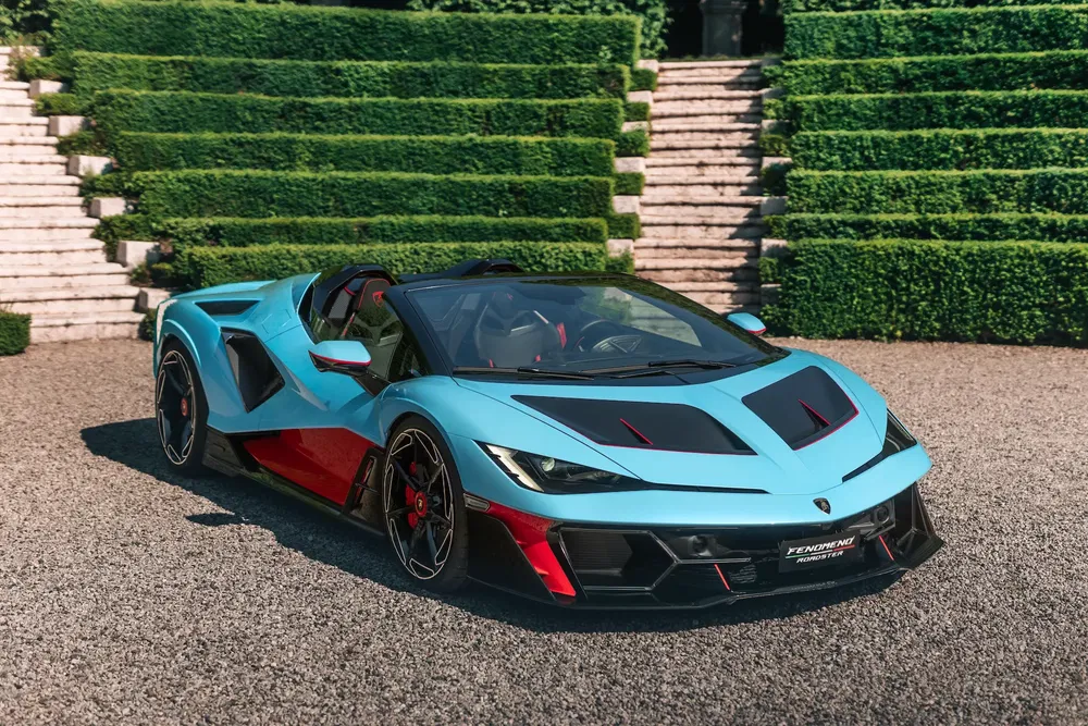 Turquoise Lamborghini roadster met rode accenten voor trappen en groen landschap.
