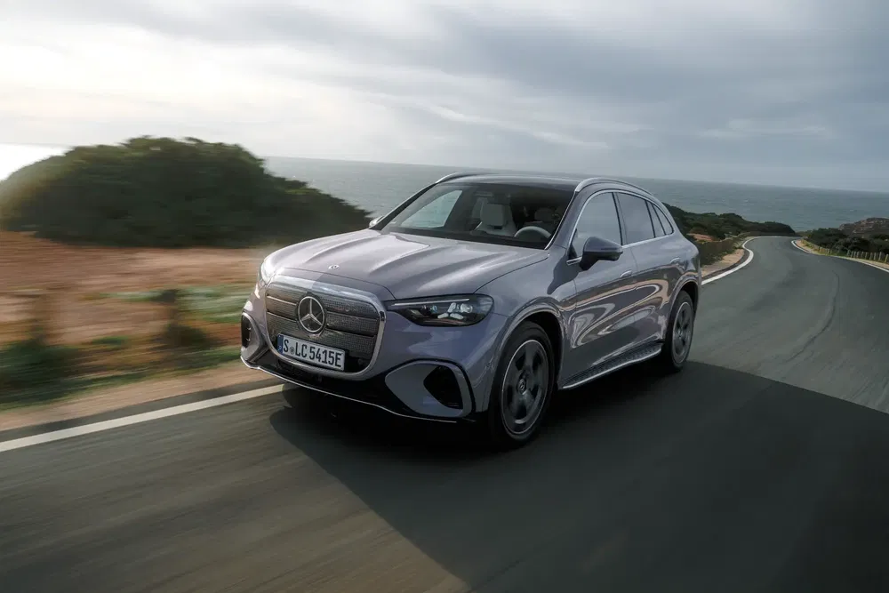 Mercedes-Benz EQS roulant sur une route côtière sinueuse avec vue sur l'horizon.