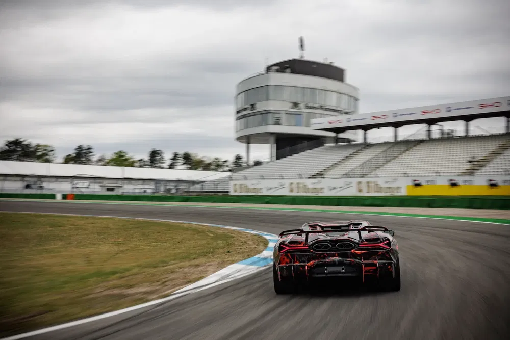 McLaren sur circuit avec ciel nuageux, tournant à grande vitesse.