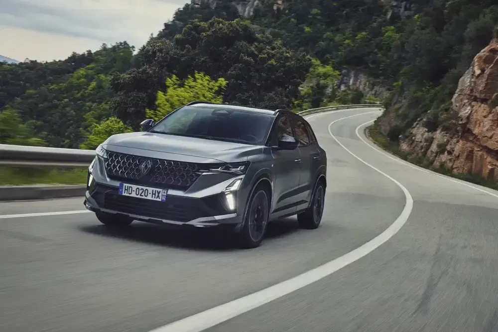 SUV DS 7 Crossback hybride roulant sur une route sinueuse de montagne verdoyante.