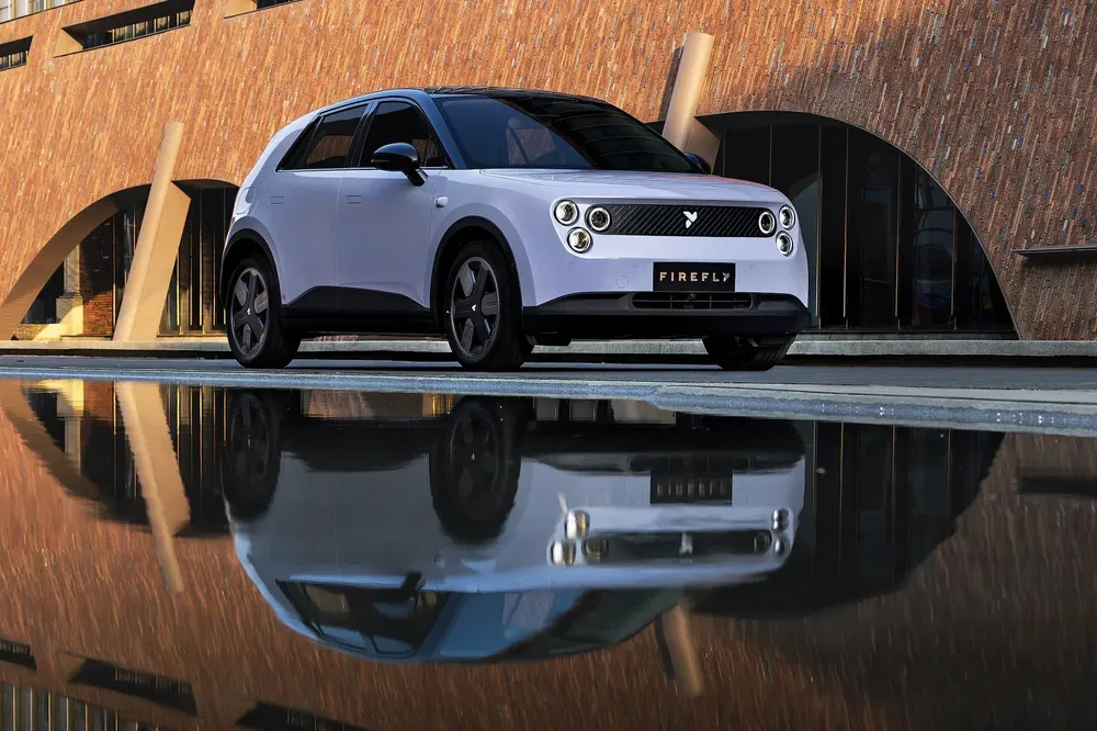 {"fr":"SUV électrique Firefly moderne réfléchissant dans une flaque d'eau devant un bâtiment architectural.","nl":"Moderne elektrische Firefly SUV weerspiegeld in een plas voor een architectonisch gebouw."}