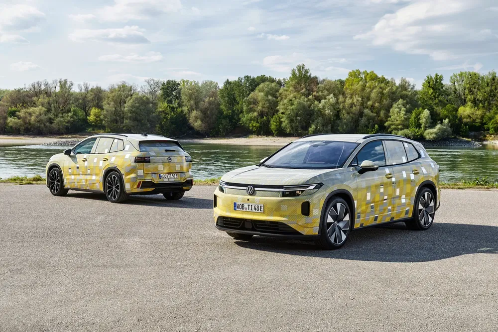 Volkswagen ID.4 stationnés près d'une rivière, carrosserie camouflée en jaune et blanc.