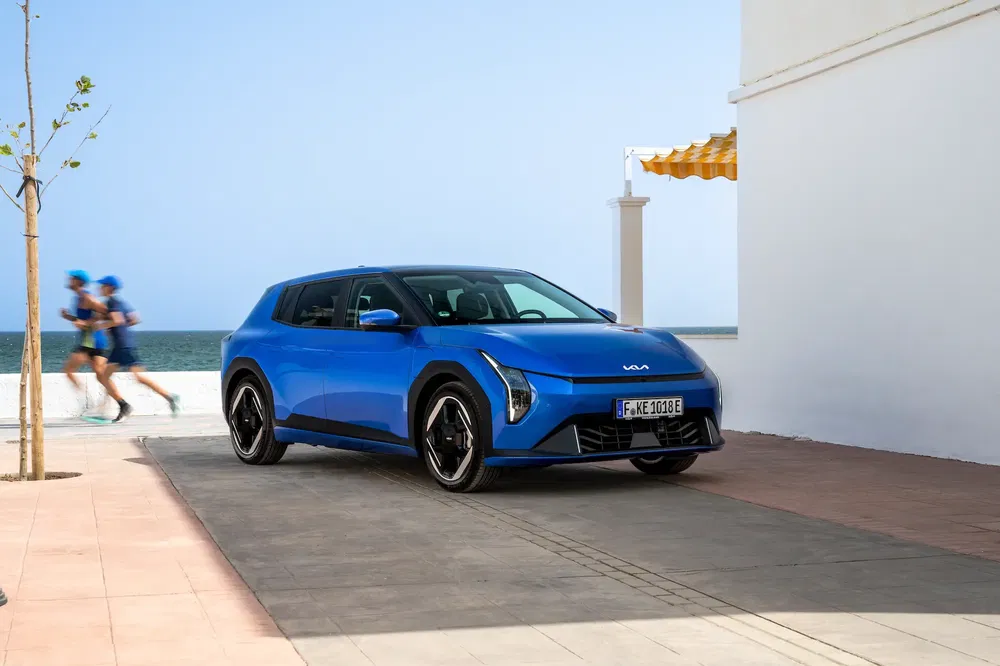 Kia électrique bleu en bord de mer, design moderne et sportif.
