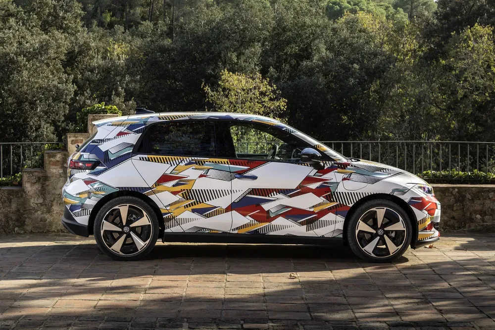 {"fr":"Volkswagen ID.2 en camouflage coloré, stationnée sur une allée pavée près d'arbres verdoyants.","nl":"Volkswagen ID.2 in kleurrijke camouflage, geparkeerd op betegelde oprit bij groene bomen."}