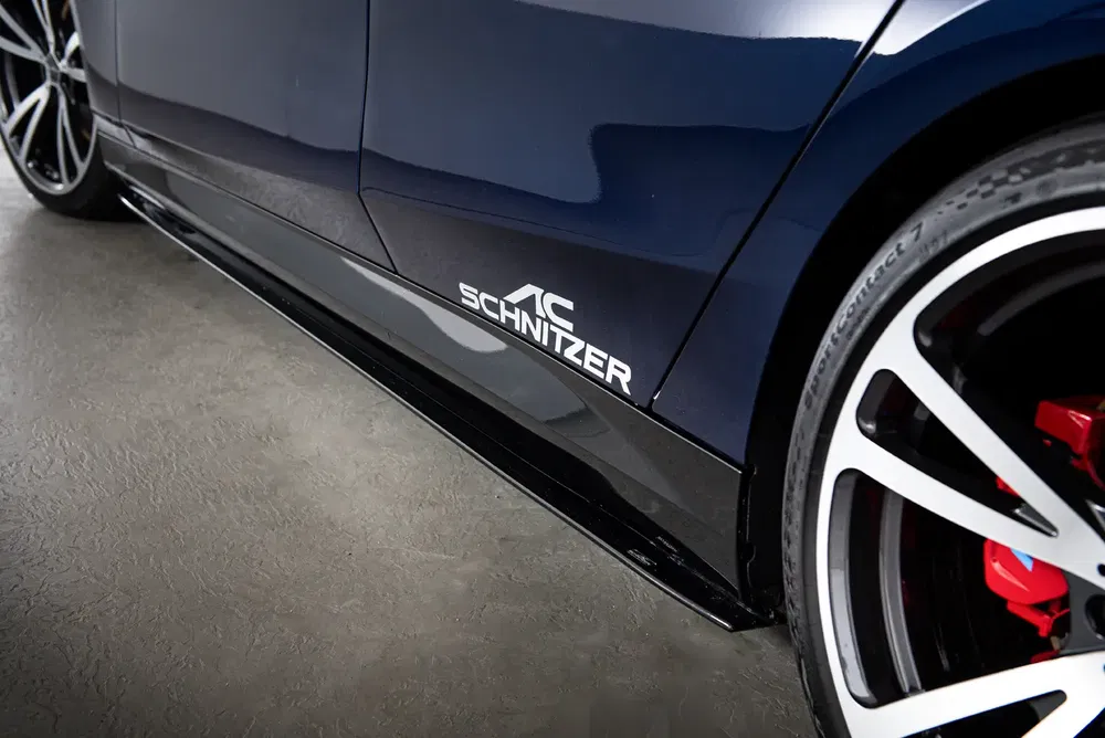 Bas de caisse AC Schnitzer sur une voiture sportive, jantes alliage noir avec étriers rouges.