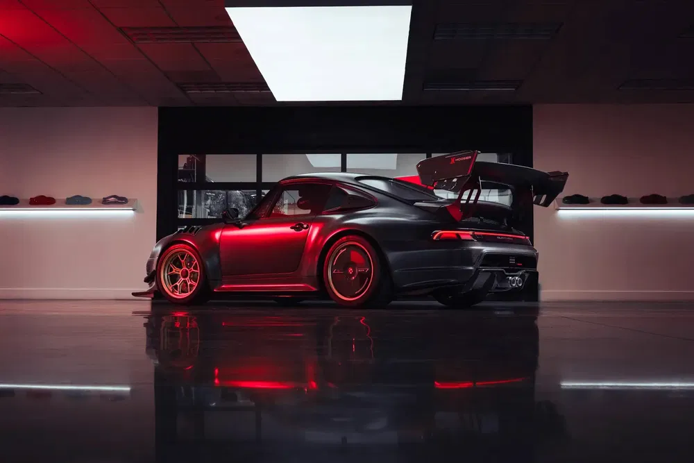 Porsche 935 moderne avec éclairage rouge dans un showroom élégant et minimaliste.