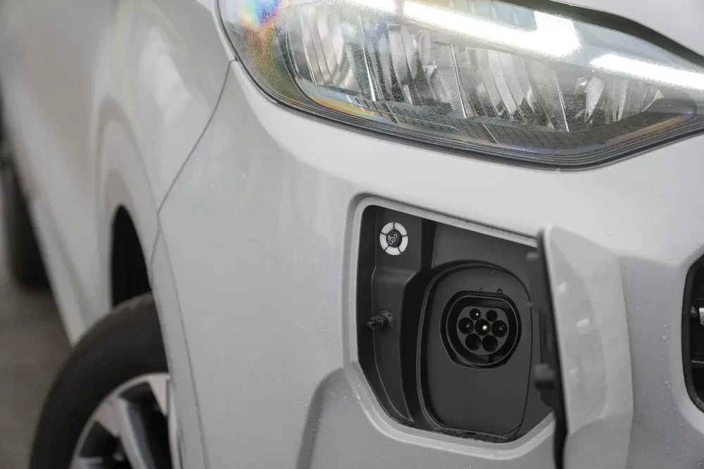 Port de recharge d'une voiture électrique blanche avec phare à LED moderne.