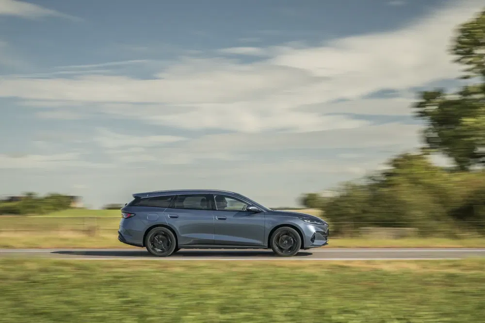 Peugeot 408 SW roulant sur une route rurale avec ciel partiellement nuageux.