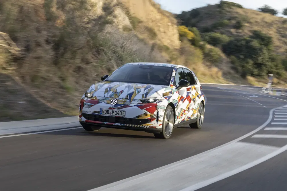 Volkswagen camouflée sur route sinueuse, testant de nouveaux designs dans un environnement montagneux.
