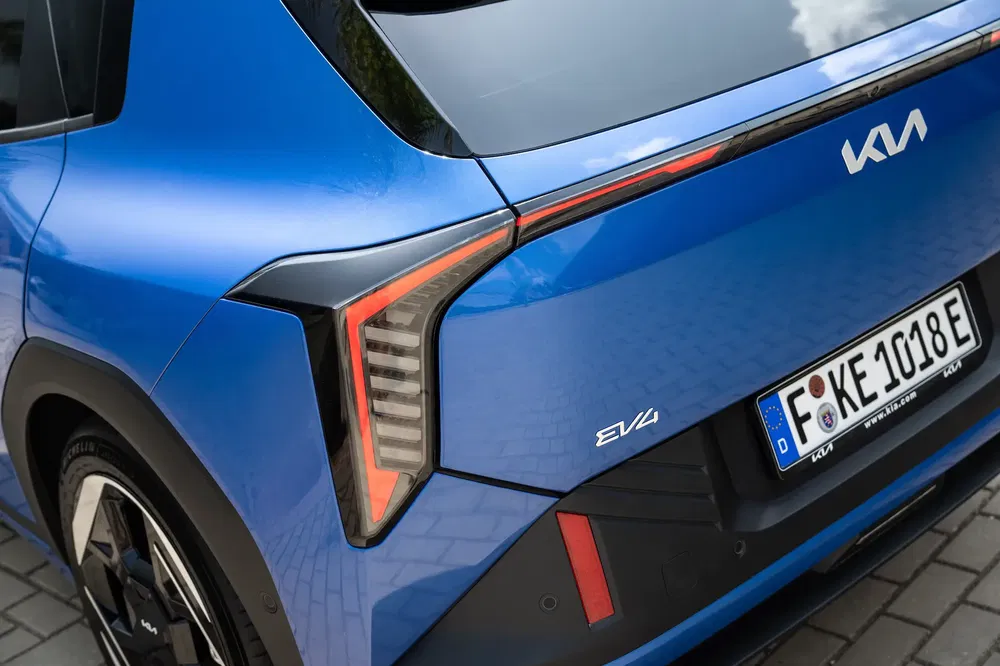 Vue arrière du véhicule électrique Kia EV4 bleu avec feux arrière distinctifs et logo Kia.