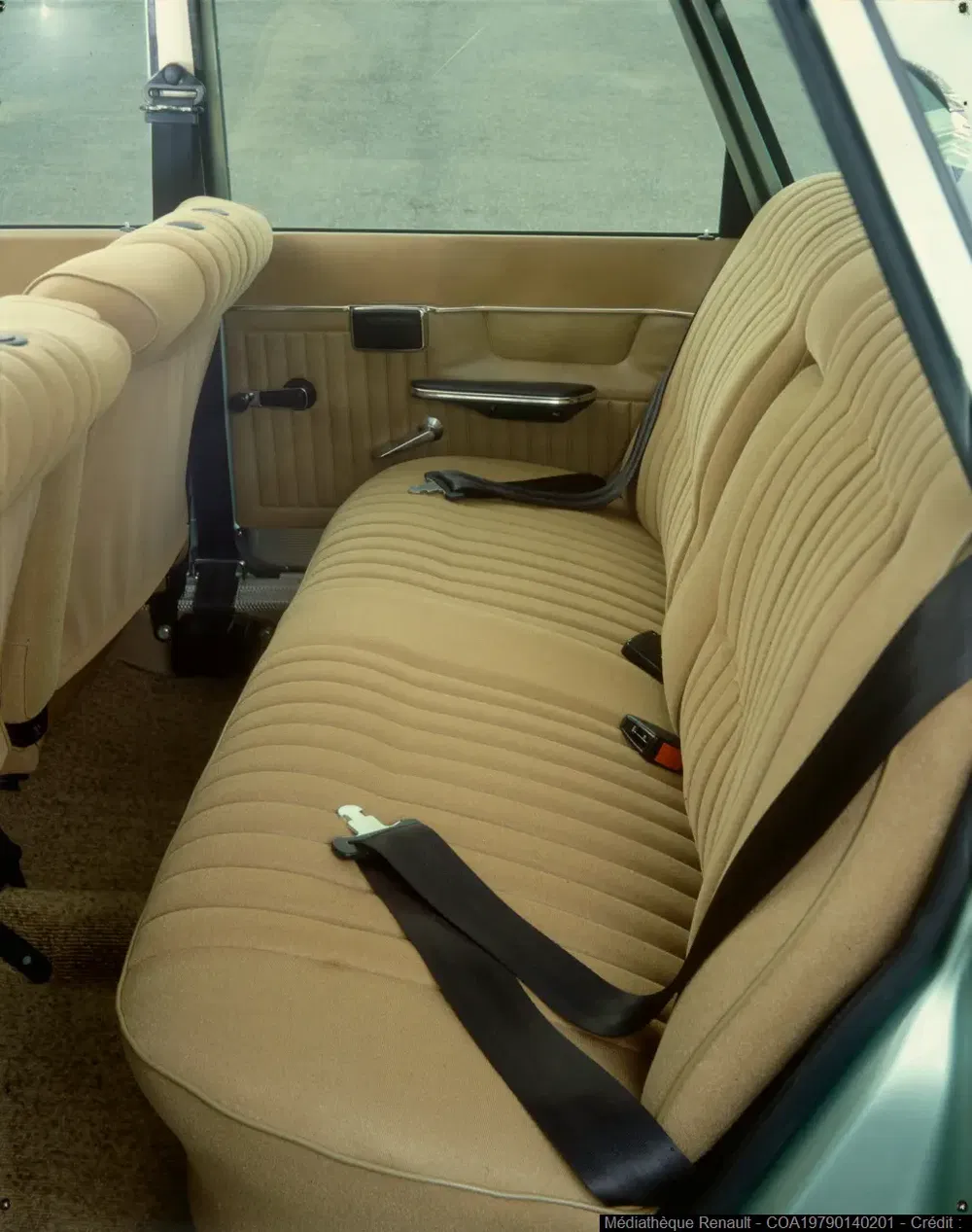 Intérieur Renault 12 avec sièges arrière beige et ceintures de sécurité noires.