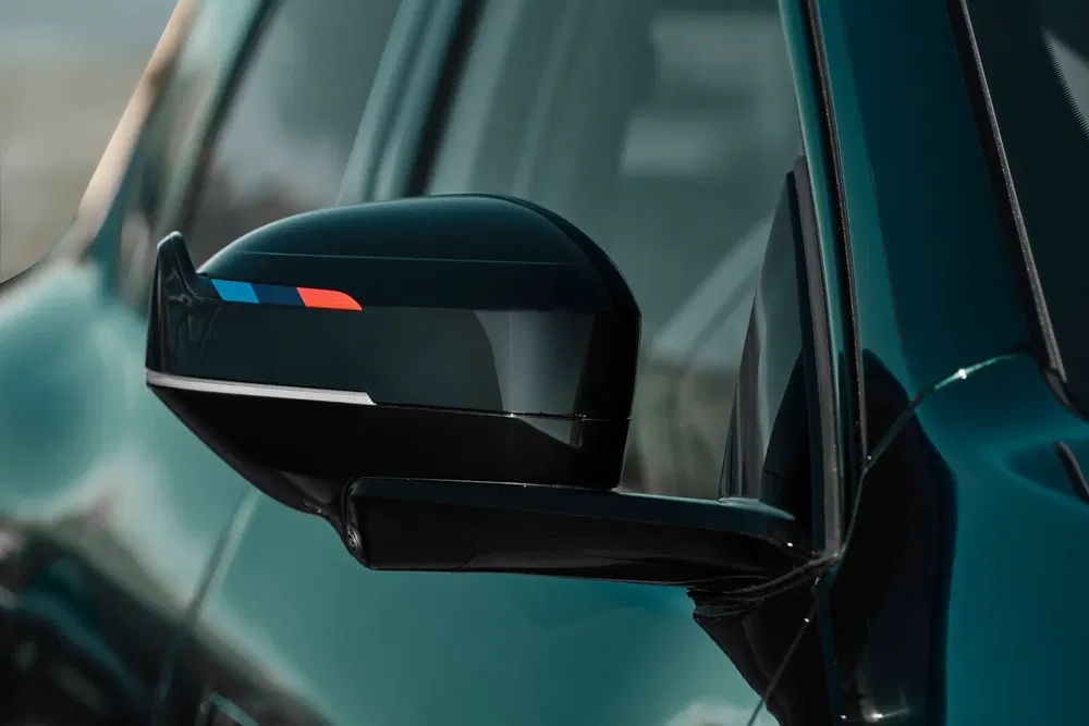 Rétroviseur BMW avec bandes M, finition noire sur peinture bleue métallique.