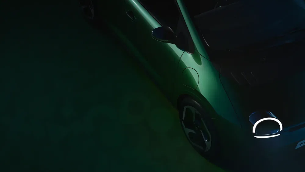 Vue aérienne d'une Fiat 500e verte dans un éclairage sombre.