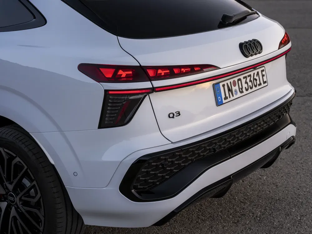 Vue arrière du SUV Audi Q3 blanc avec feux arrière et plaque allemande visibles.