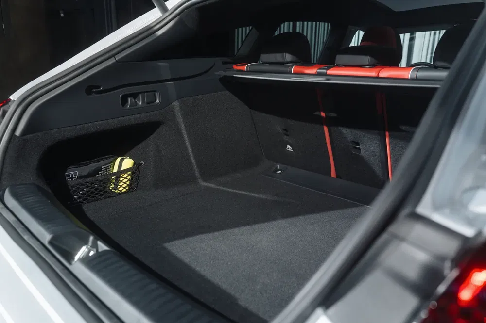 Coffre spacieux de voiture avec intérieur noir et détails rouges sur les sièges arrière.