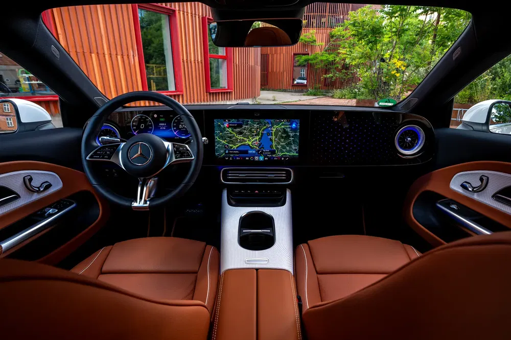 Luxe interieur Mercedes-Benz met bruine lederen stoelen en modern digitaal dashboard.