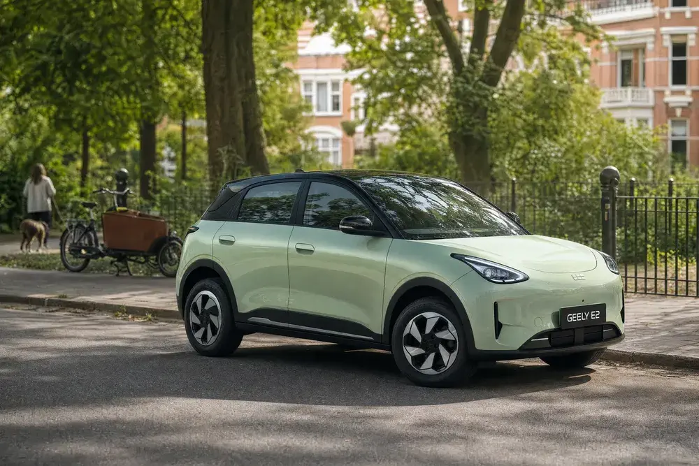 Voiture Geely E2 électrique vert pâle garée dans une rue bordée d'arbres.