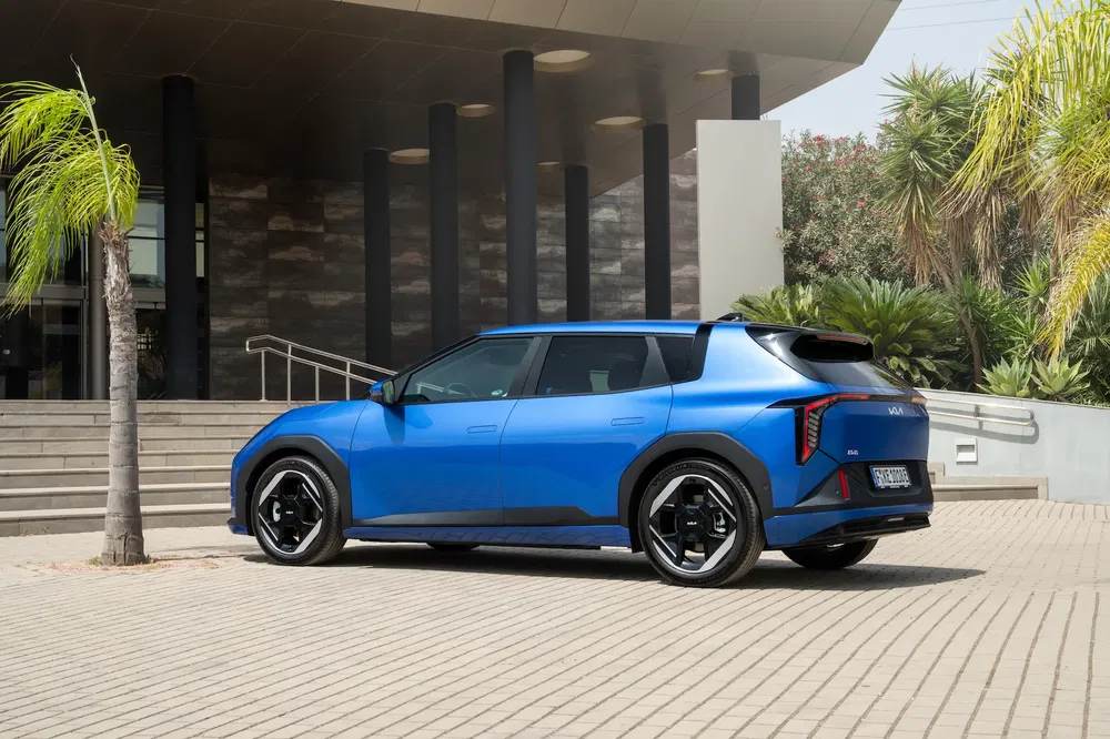 Kia EV9 bleue garée devant un bâtiment moderne, design élégant et futuriste.