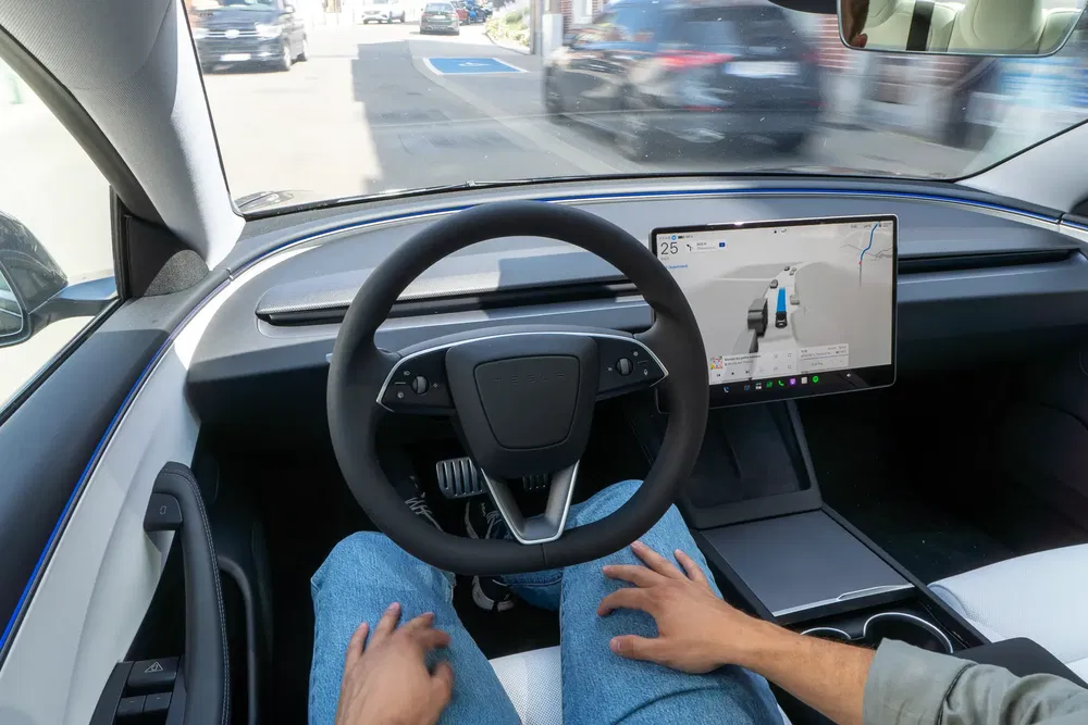 Intérieur d'une voiture autonome avec volant et écran de navigation affichant la route.