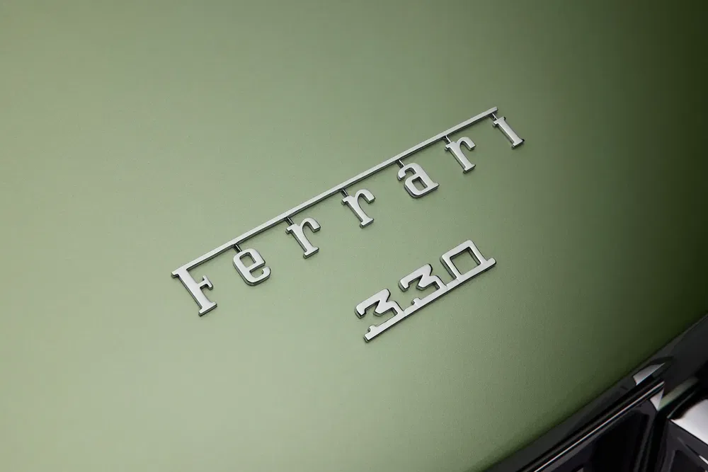 Logo Ferrari 330 sur carrosserie verte minimaliste d'une voiture classique.