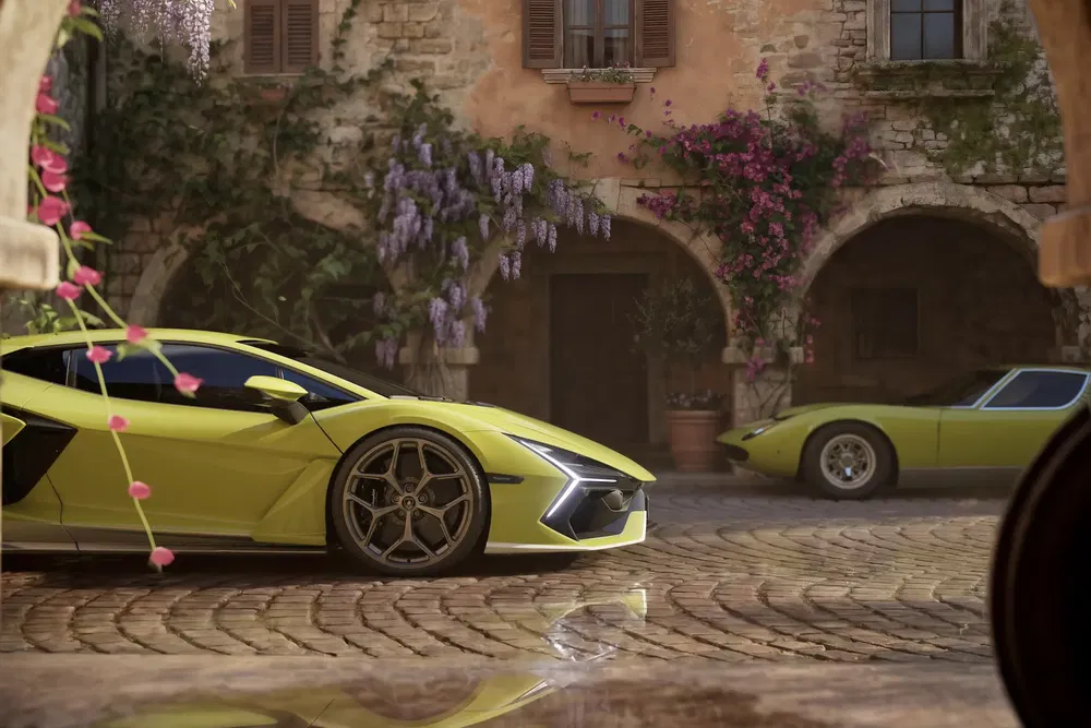 Lamborghini jaune vif garée sur une cour pavée, entourée de fleurs et architecture italienne.