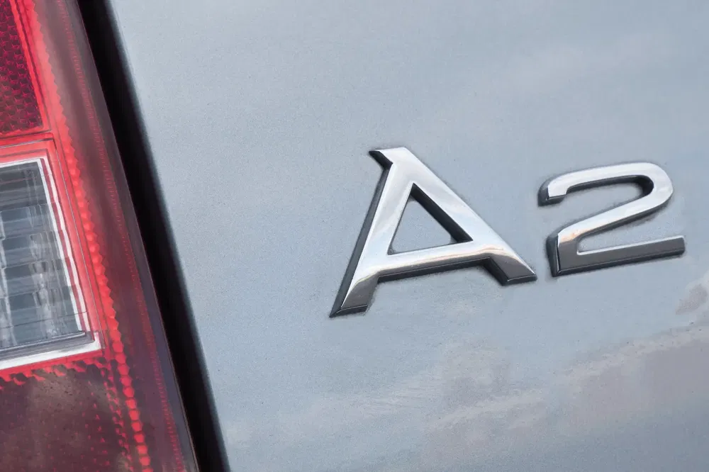 {"fr":"Insigne Audi A2 sur arrière de voiture grise avec feu arrière visible.","nl":"Audi A2-badge op grijze auto met zichtbaar achterlicht."}