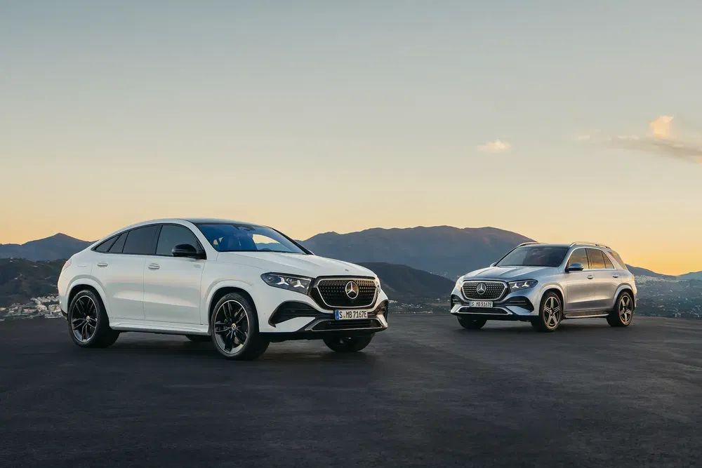Deux Mercedes-Benz GLE blanches et argentées sur fond de montagnes au crépuscule.