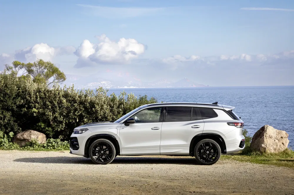 Witte Changan CS95 geparkeerd bij zee met panoramisch uitzicht en blauwe lucht.