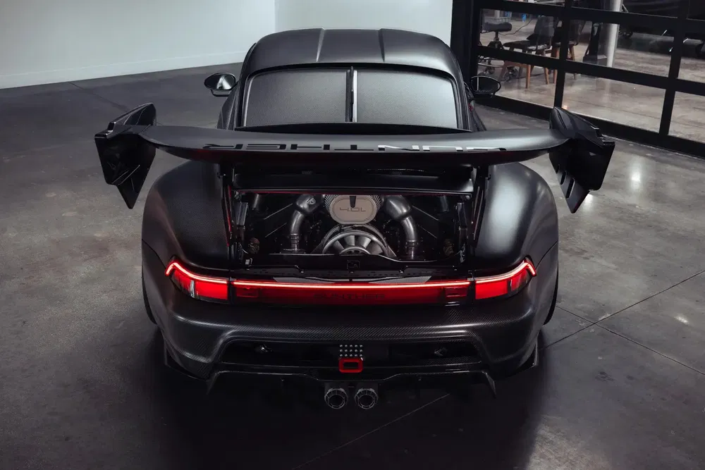 Vue arrière d'une Porsche 911 avec moteur exposé, aileron imposant et éclairage LED moderne.