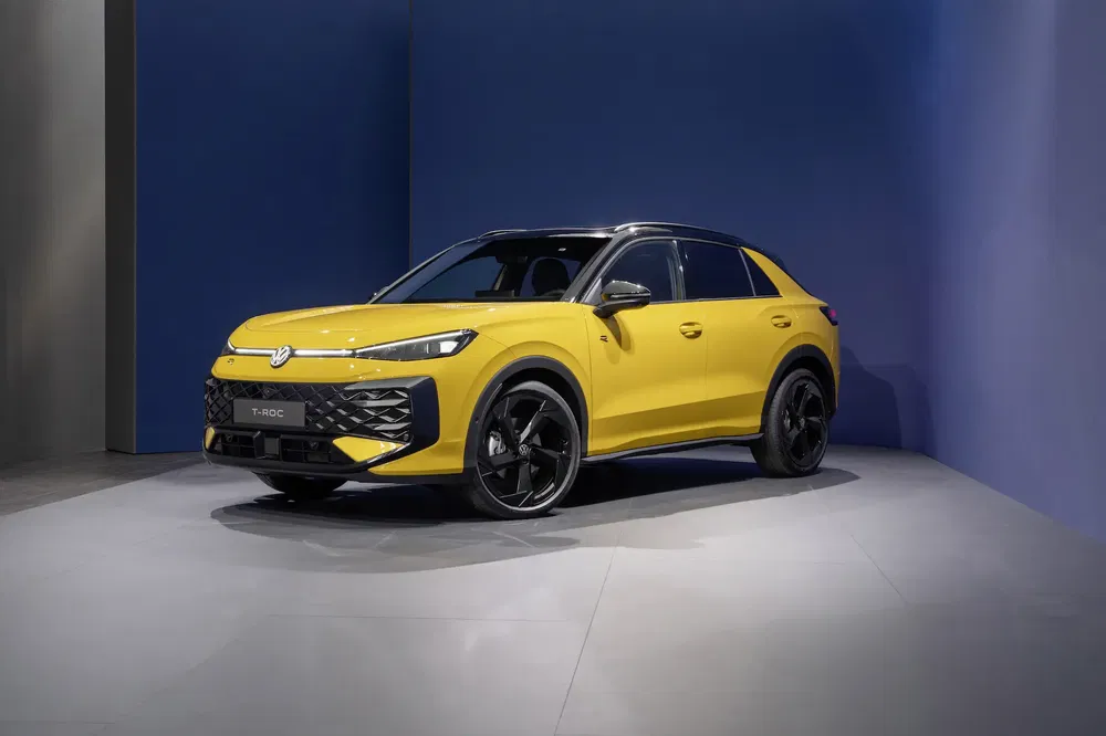 Volkswagen T-Roc jaune vif exposé dans un showroom moderne avec un fond bleu.