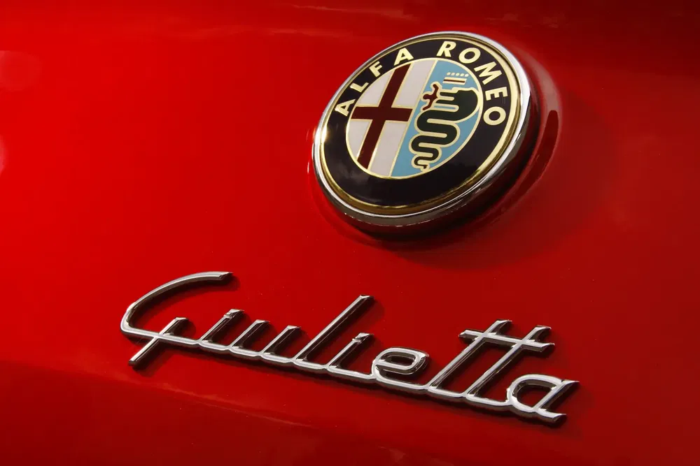 Logo Alfa Romeo Giulietta sur capot rouge, emblème de voiture italienne emblématique.