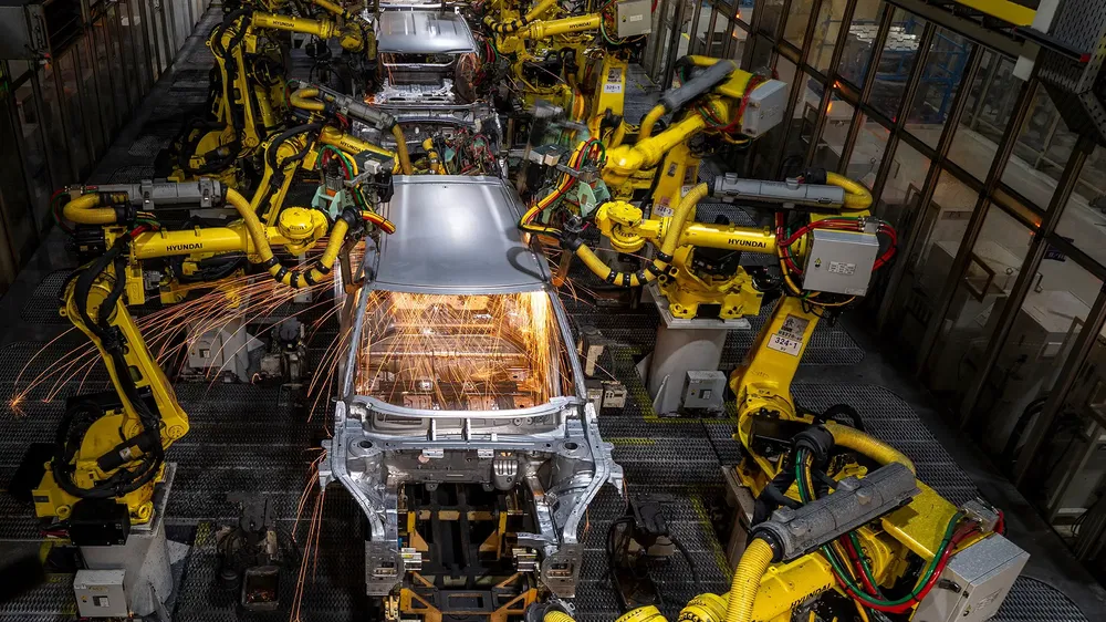 Hyundai-fabriek met robots die auto's assembleren, zichtbare vonken tijdens productieproces.