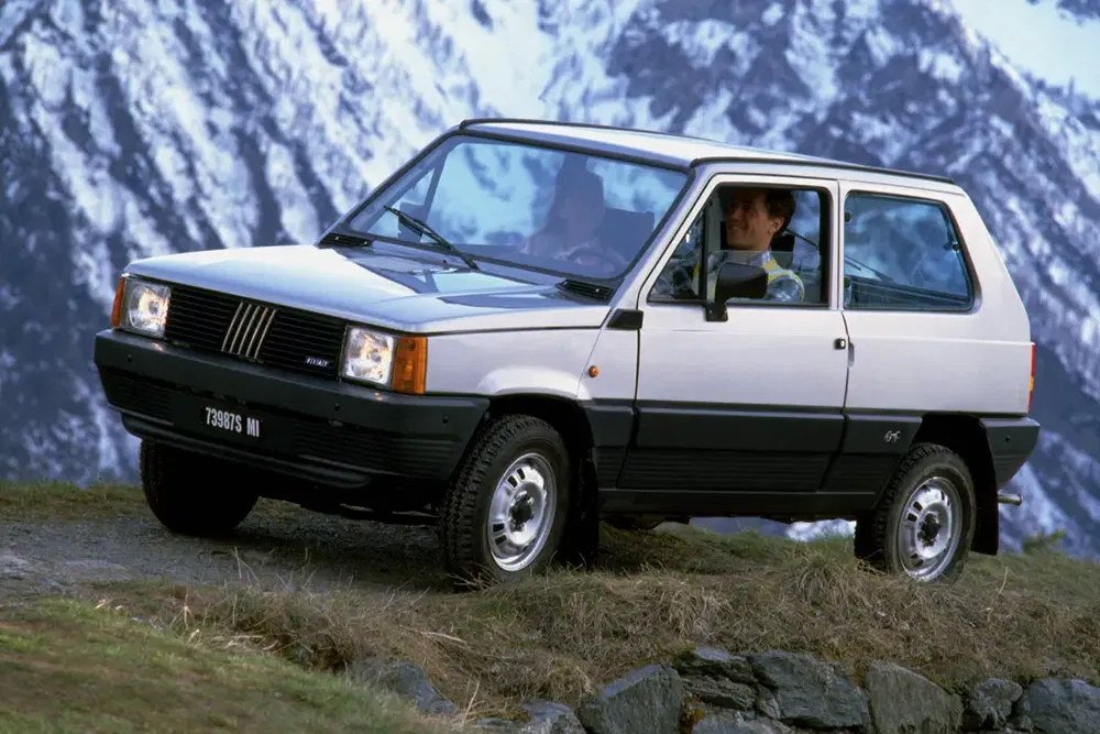 Fiat Panda 4x4 uit de jaren 80, besneeuwd berglandschap op de achtergrond.