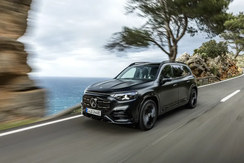 Mercedes GLC moderne conduisant sur une route côtière pittoresque avec vue sur l'océan.