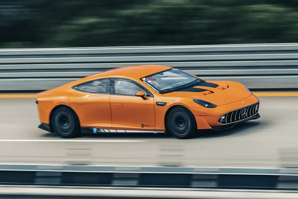 Voiture électrique orange en mouvement sur autoroute, design aérodynamique et sportif.