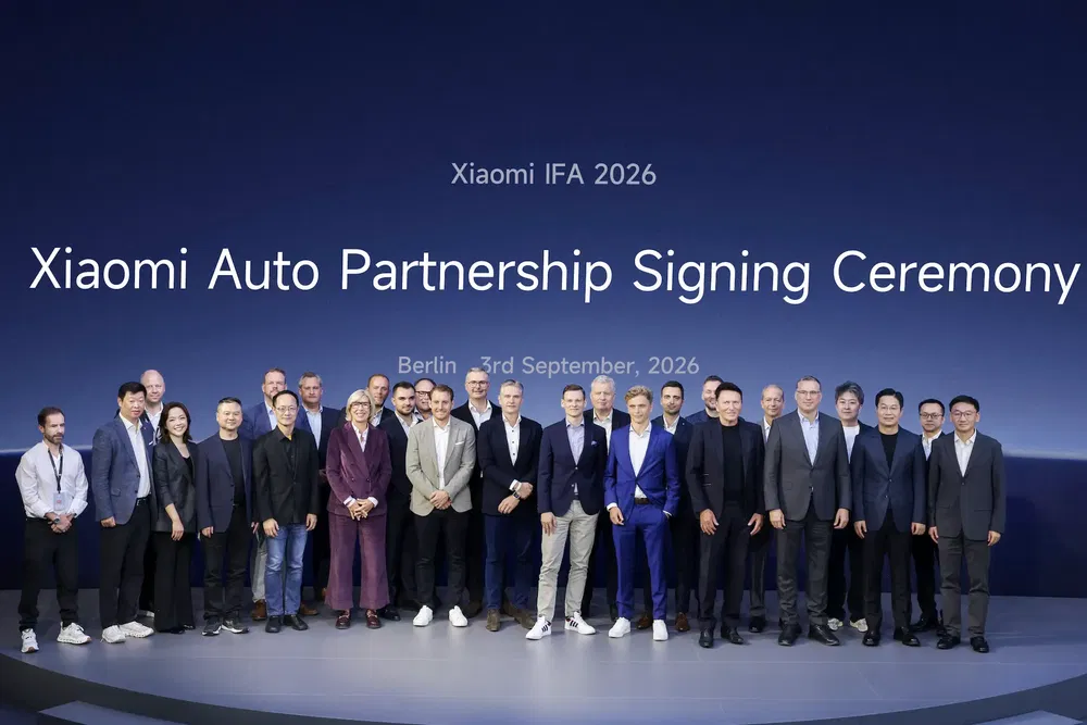 Cérémonie de signature de partenariat auto Xiaomi, IFA 2026 à Berlin, groupe de personnes sur scène.