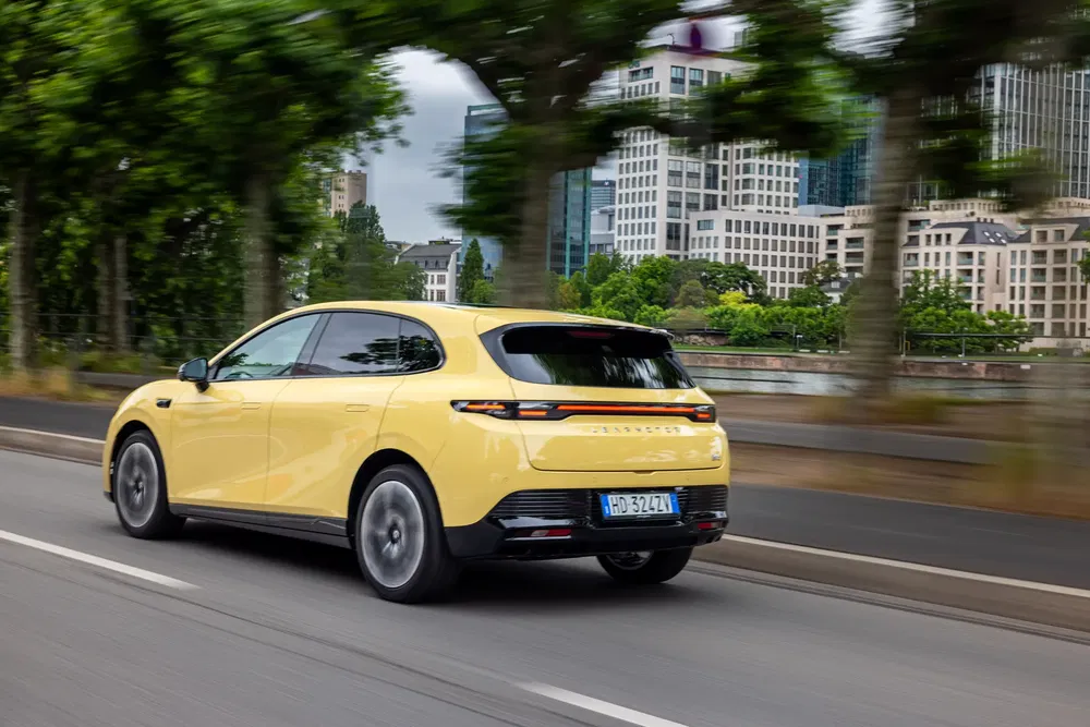 MG4 électrique jaune roulant en ville avec des immeubles modernes en arrière-plan.