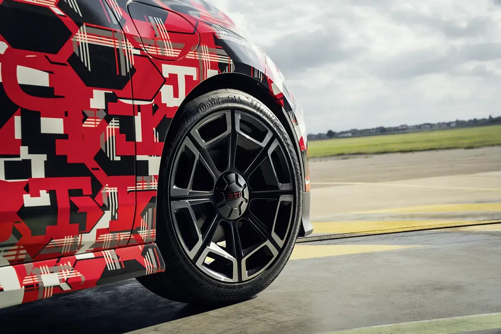 Vue rapprochée d'une roue Audi camouflée avec des motifs rouges et noirs dynamiques.