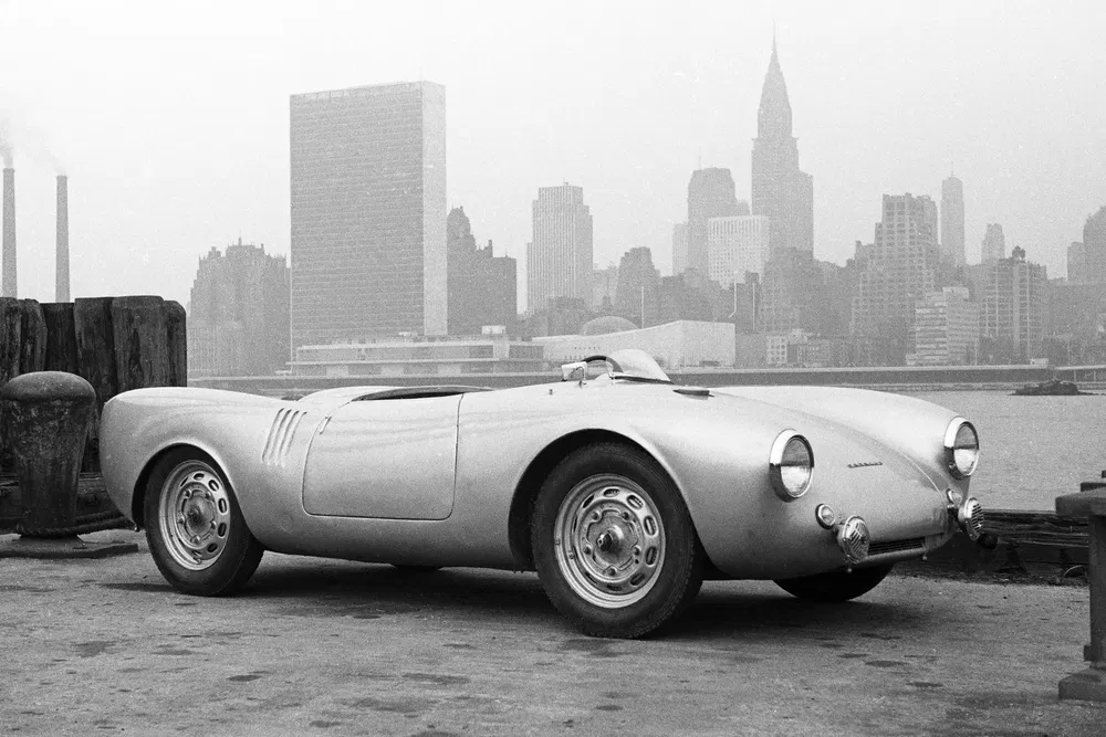 Klassieke Porsche 550 Spyder voor mistige stadsachtergrond, vintage elegantie in zwart-wit.