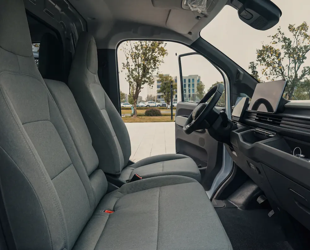 Moderne interieur van een elektrische bedrijfsvoertuig met grijze stoffen stoelen.