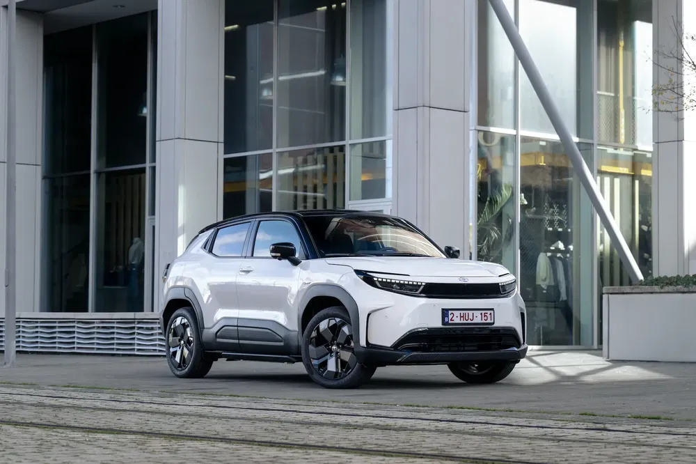 SUV électrique blanc stationné devant un immeuble moderne, design épuré et élégant.