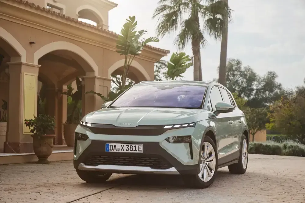 SUV Skoda moderne stationné devant une villa élégante, arbres et architecture méditerranéenne.