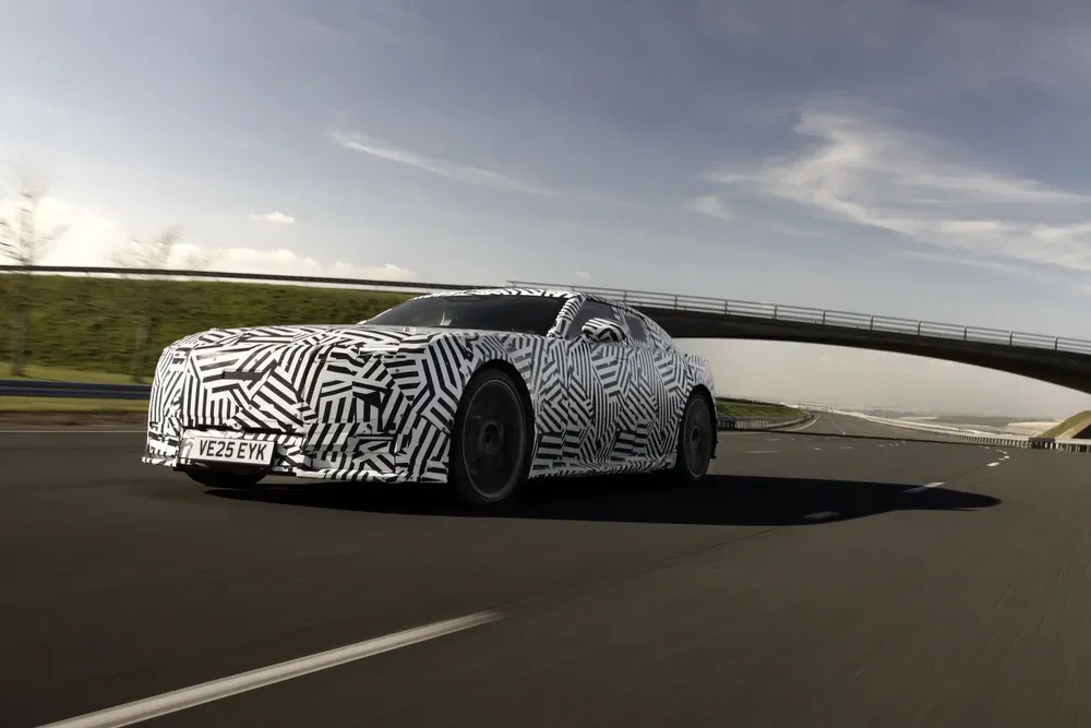 Camouflage prototype auto tijdens testrit op snelweg onder een brug.