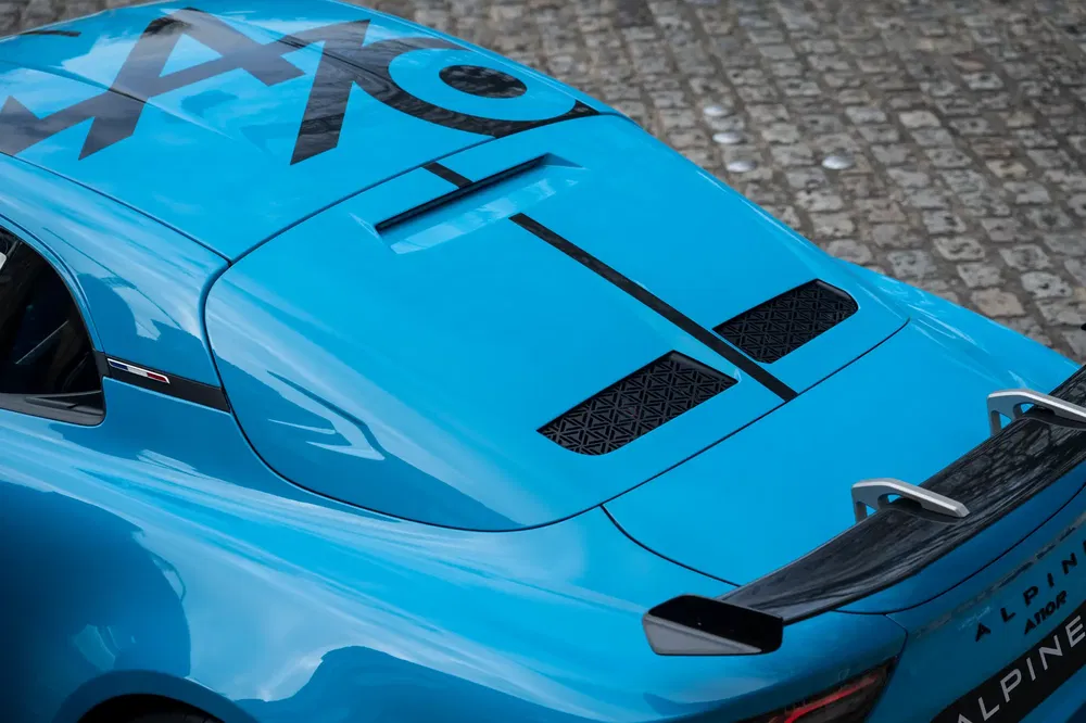Achteraanzicht van de blauwe Alpine A110 met achterspoiler en opvallend ontwerp.