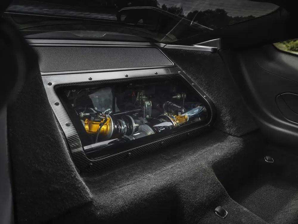 Vue intérieure d'une McLaren avec moteur visible à travers une fenêtre en fibre de carbone.